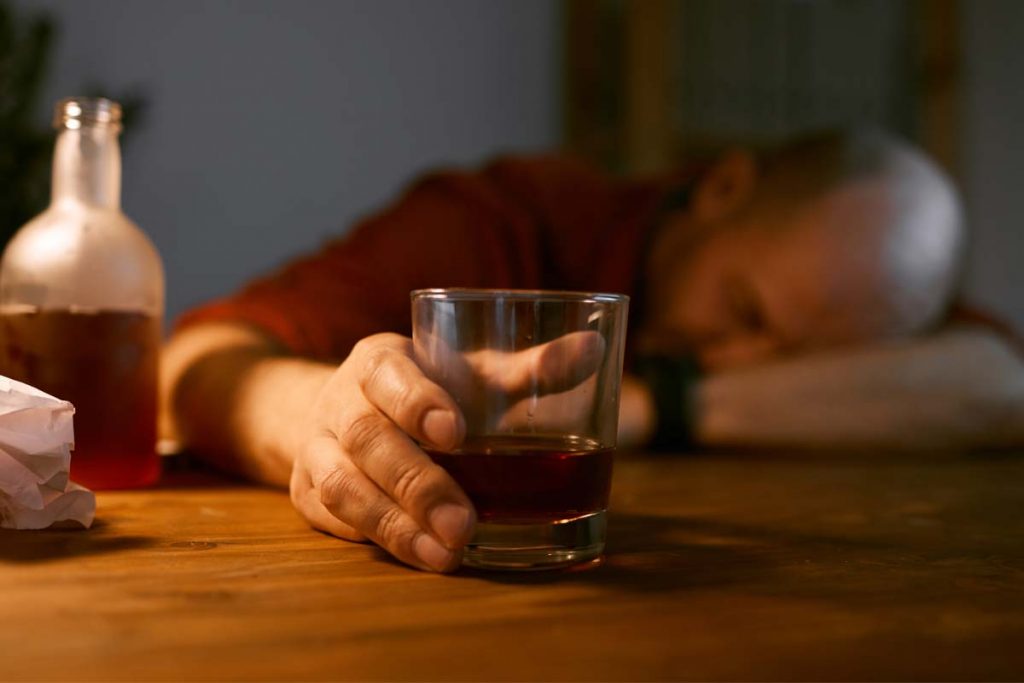 man holding glass showing signs of alcohol overdose