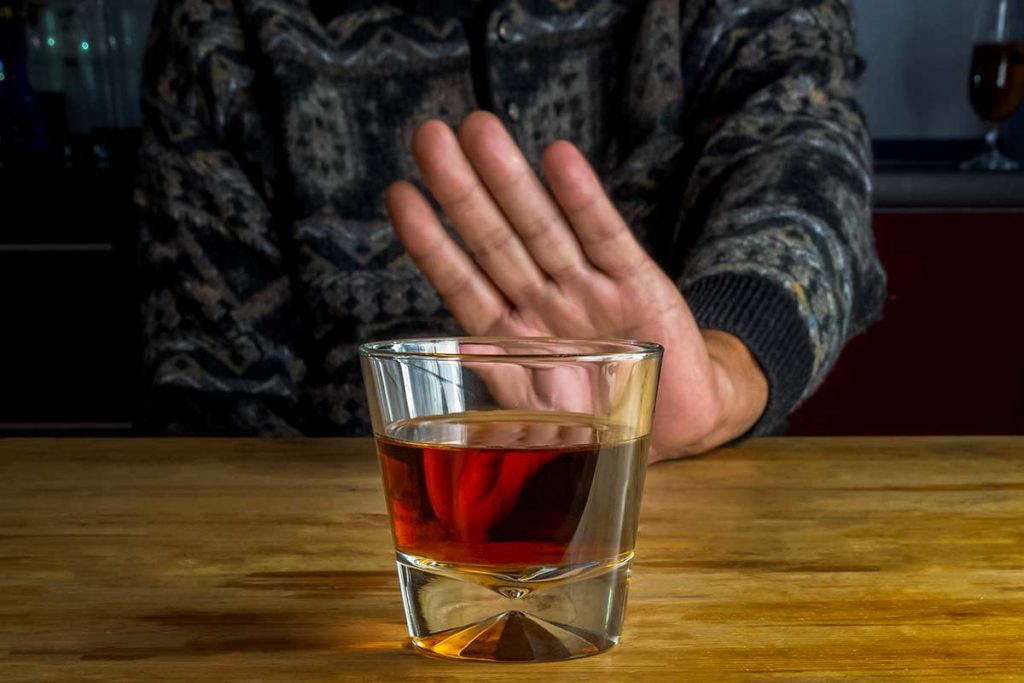 individual saying no to alcohol to stay sober during a crisis
