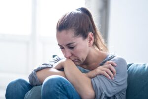 a sad woman on a couch thinking about the common myths about addiction